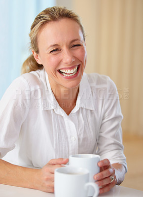 Buy stock photo Happy mature woman, laughing and coffee for funny joke, conversation or humor on kitchen table at home. Blonde female person smile or laugh with cup of tea for meme, discussion or fun chat at house