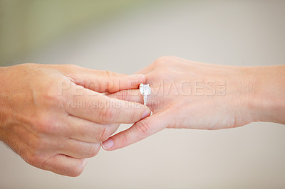 Buy stock photo Cropped view of a man's hand sliding a wedding ring onto a woman's ring finger