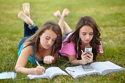 Buy stock photo Teenage girls lying together on a lawn doing their homework