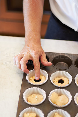 Buy stock photo Hands, closeup and tray with berry on cupcake in bakery, cafe or kitchen with professional chef. Baker, muffin and start with dough, blackberry or job at small business, restaurant or coffee shop