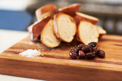 Buy stock photo Olives, food and bakery with bread in kitchen for nutrition, health and diet. Breakfast, cafe and coffee shop with closeup of product on cutting board on table for wheat, grain and cooking