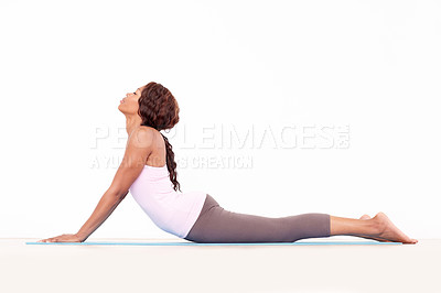 Buy stock photo Yoga, cobra back stretch and black woman relax in studio on a fitness and workout mat for training. Isolated, white background and calm African female person lying on the ground with body stretching