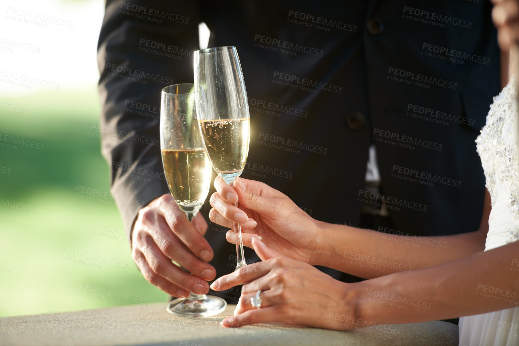 Buy stock photo Cropped view of a young bride and groom standing together and toasting their marriage