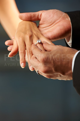 Buy stock photo Cropped view of a groom slipping a ring on to his bride's finger