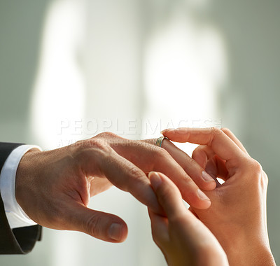 Buy stock photo Cropped view of a bride slipping a ring on to her groom's finger