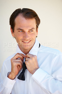 Buy stock photo A handsome young man tying his bow tie