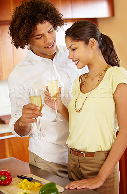 Buy stock photo A young couple toasting each other in their kitchen