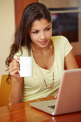 Buy stock photo A young woman using her laptop in the kitchen