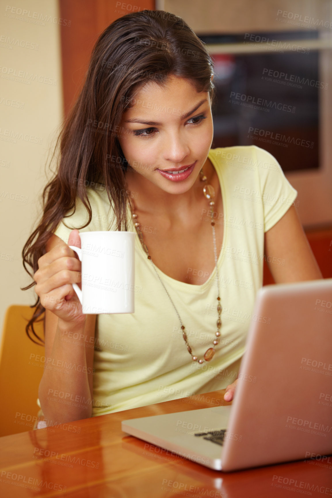 Buy stock photo A young woman using her laptop in the kitchen