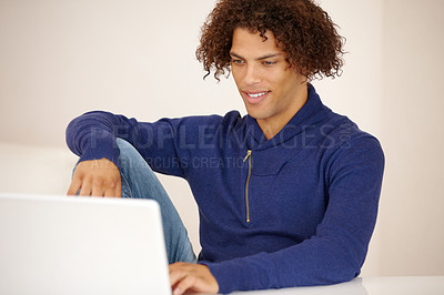 Buy stock photo Handsome young ethnic man working on his laptop on his couch