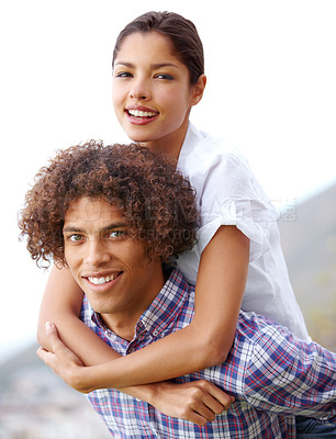 Buy stock photo Shot of a handsome young man giving his girlfriend a piggyback outdoors