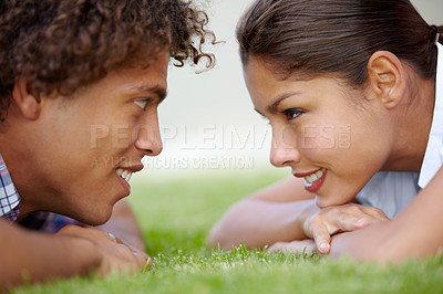 Buy stock photo Shot of a happy young couple gazing into each other's eyes on the lawn