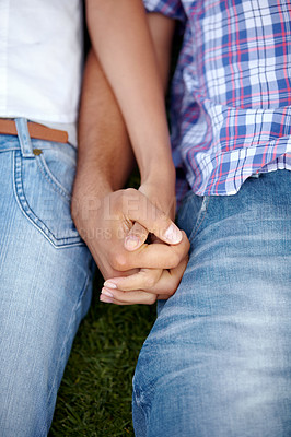 Buy stock photo Cropped shot of a couple holding hands while lying together on the lawn