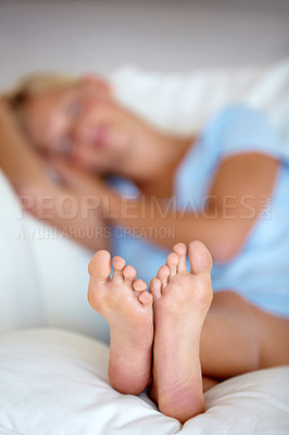 Buy stock photo Shot of a tired woman sleeping on her bed, focus on feet
