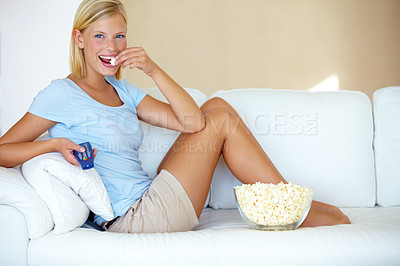 Buy stock photo Young woman sitting on the couch and watching tv while eating popcorn
