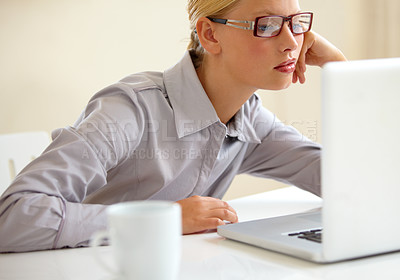 Buy stock photo A bored, tired young businesswoman staring at her laptop screen