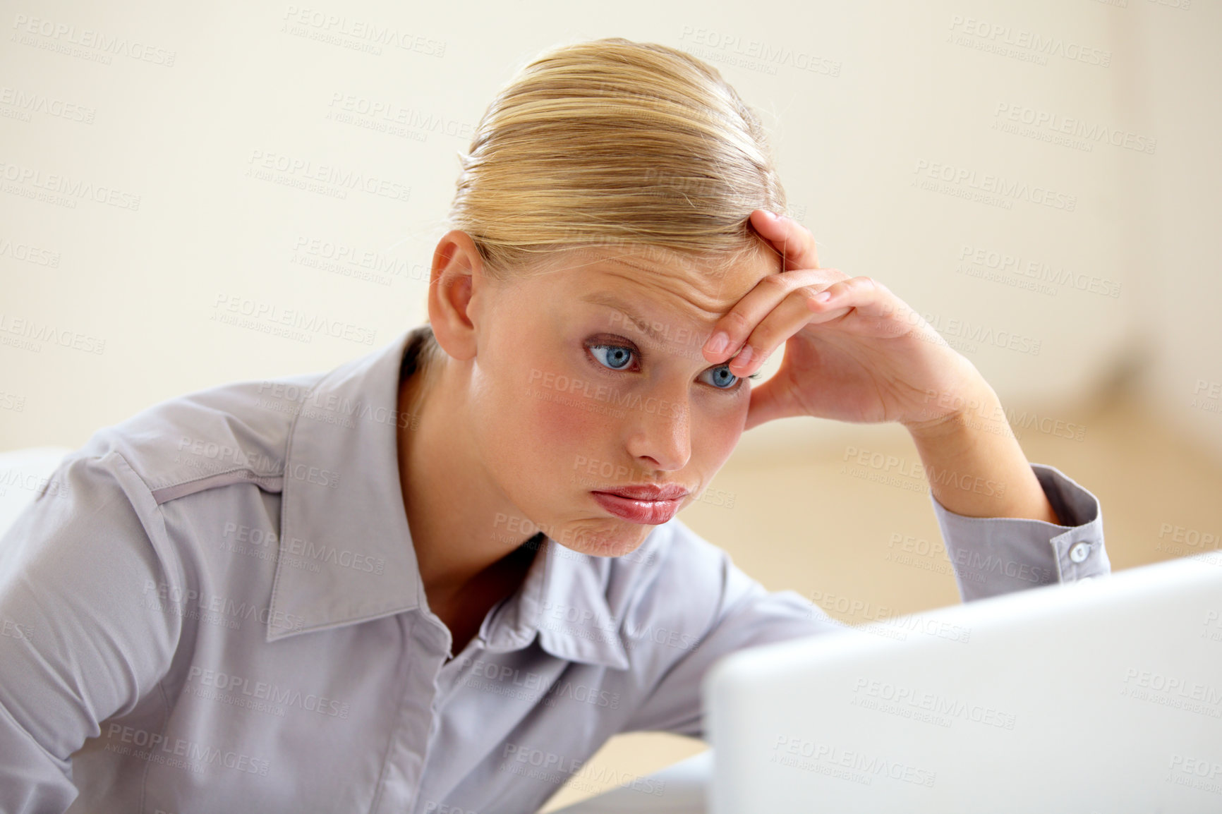 Buy stock photo An exhausted young woman looking at her laptop screen with a frown