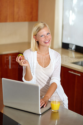 Buy stock photo A lovely young woman using her laptop while enjoying a healthy breakfast