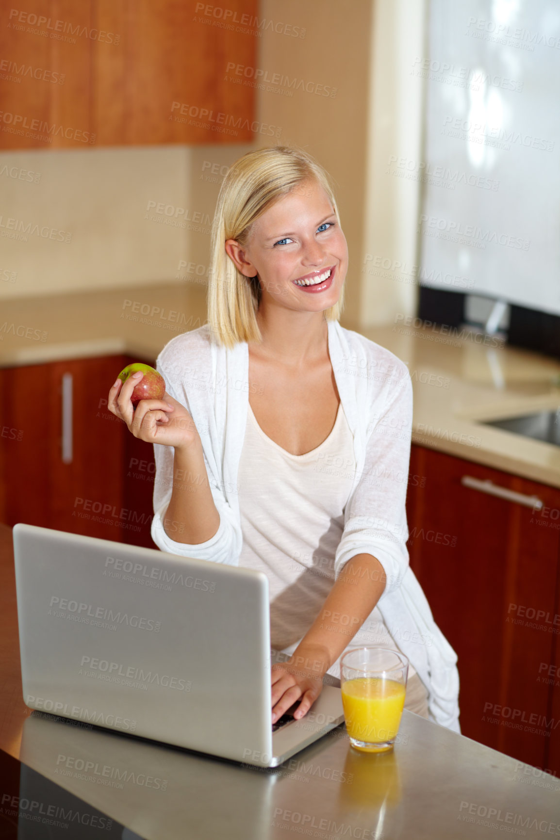 Buy stock photo A lovely young woman using her laptop while enjoying a healthy breakfast