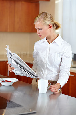 Buy stock photo A pretty young professional reading the morning paper while enjoying coffee and breakfast