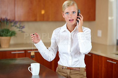Buy stock photo A beautiful young woman receiving an astonishing call while making tea