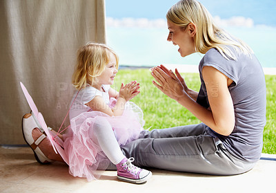 Buy stock photo A mother and daughter clapping along to a beat and smiling at each other