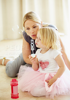 Buy stock photo A mother blowing bubbles with her young daughter