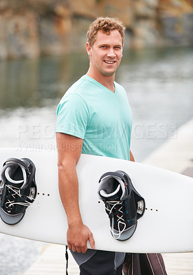 Buy stock photo Smiling wakeboarder holding his wakeboard alongside the lake