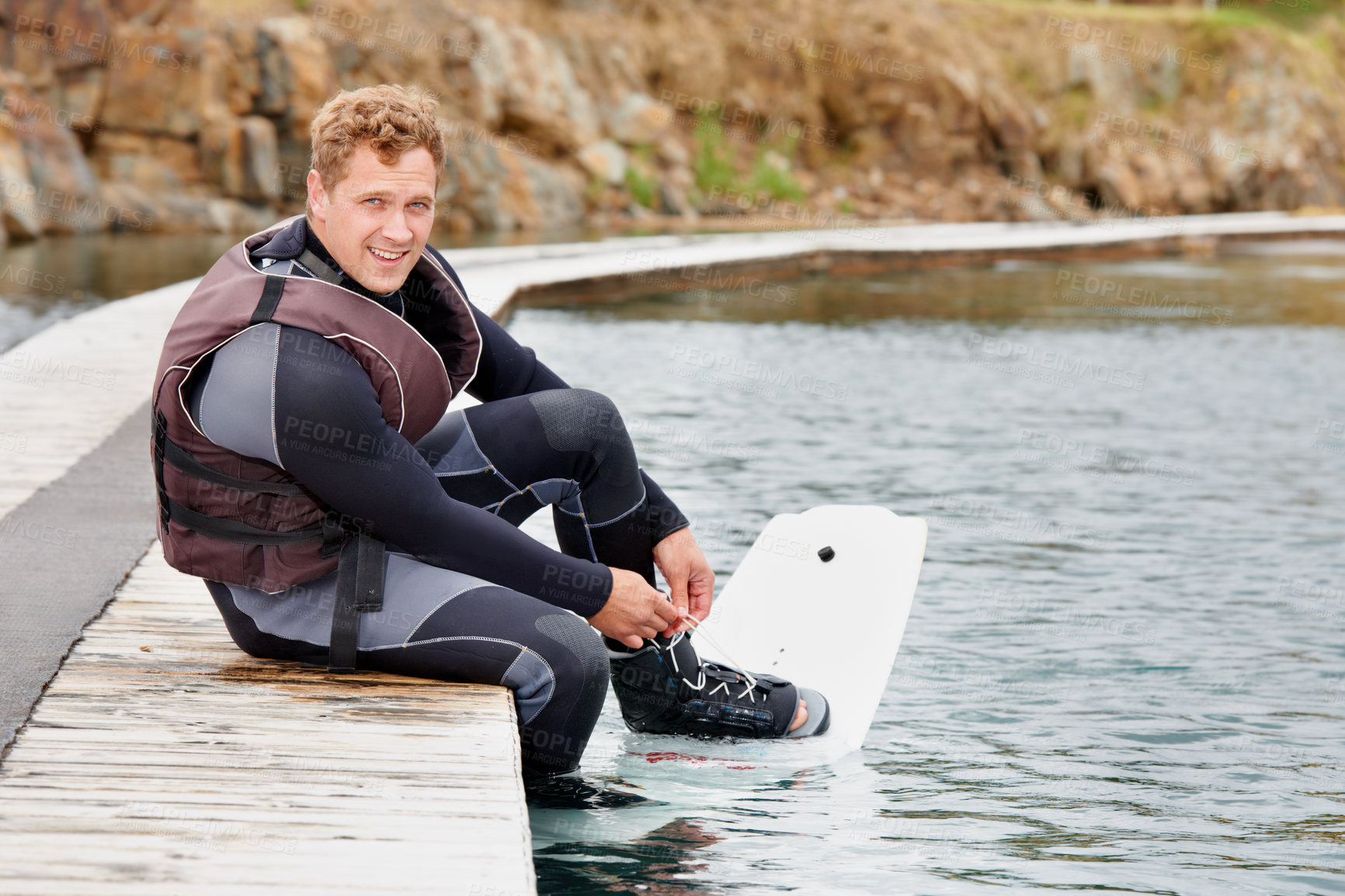 Buy stock photo Young guy waiting to get out on the lake for some wakeboarding