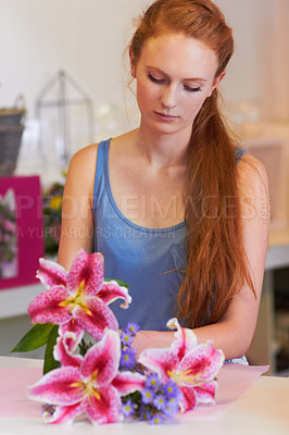 Buy stock photo Beautiful young woman arranging lillies into a floral bouquet