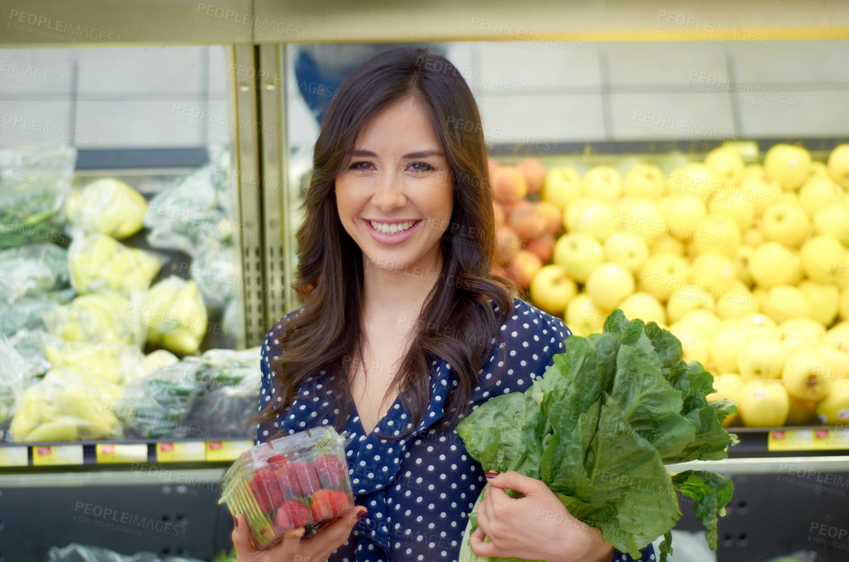 Buy stock photo A young woman smiling while buying vegetables