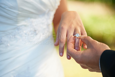 Buy stock photo Closeup of a groom putting the ring on his bride's finger on their wedding day