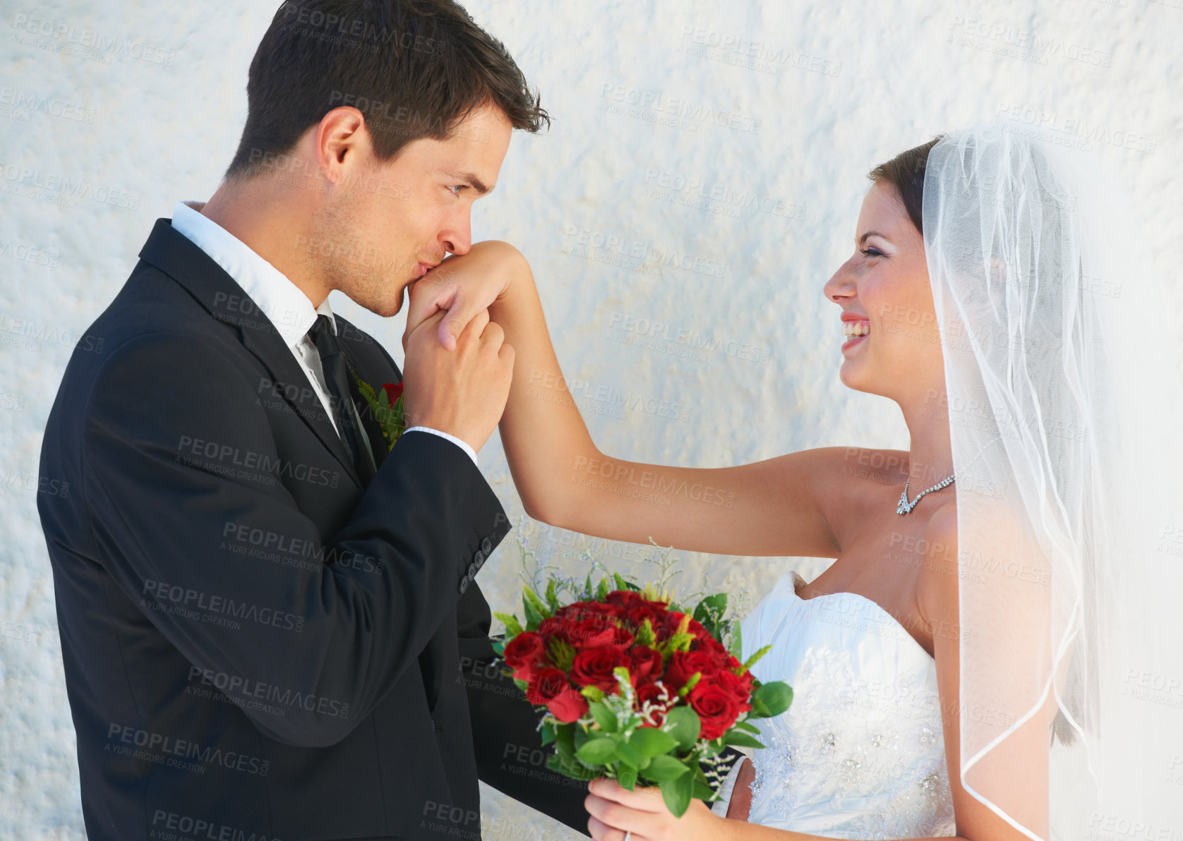 Buy stock photo Love, happy couple and kiss on hand at wedding with smile, rose bouquet and commitment at reception. Flowers, woman and man embrace at marriage celebration with romance, loyalty and future together.