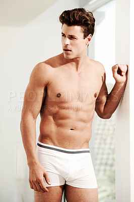 Buy stock photo A muscular young man wearing only his boxers leaning against a wall