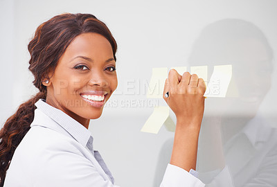 Buy stock photo An african american woman sticking post-its onto a glass wall