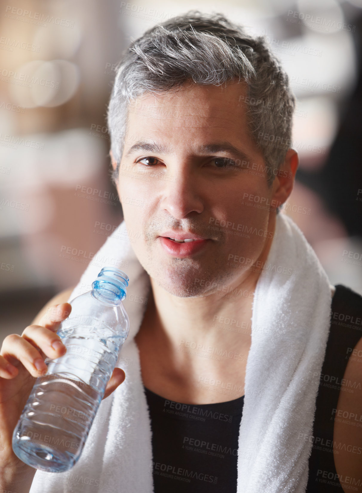 Buy stock photo Portrait of a mature man drinking from a water bottle after an intense workout at gym