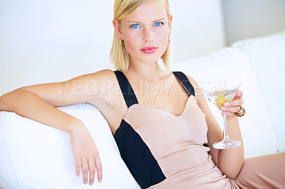 Buy stock photo Beautiful young blonde woman sitting on a white couch drinking a martini