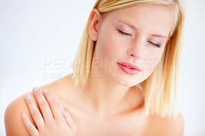 Buy stock photo Relaxed young woman touching her skin against a white background