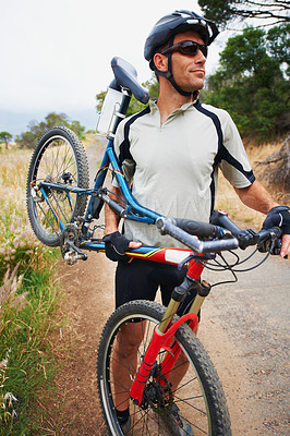 Buy stock photo Shot of a sportsman carrying his mountain bike
