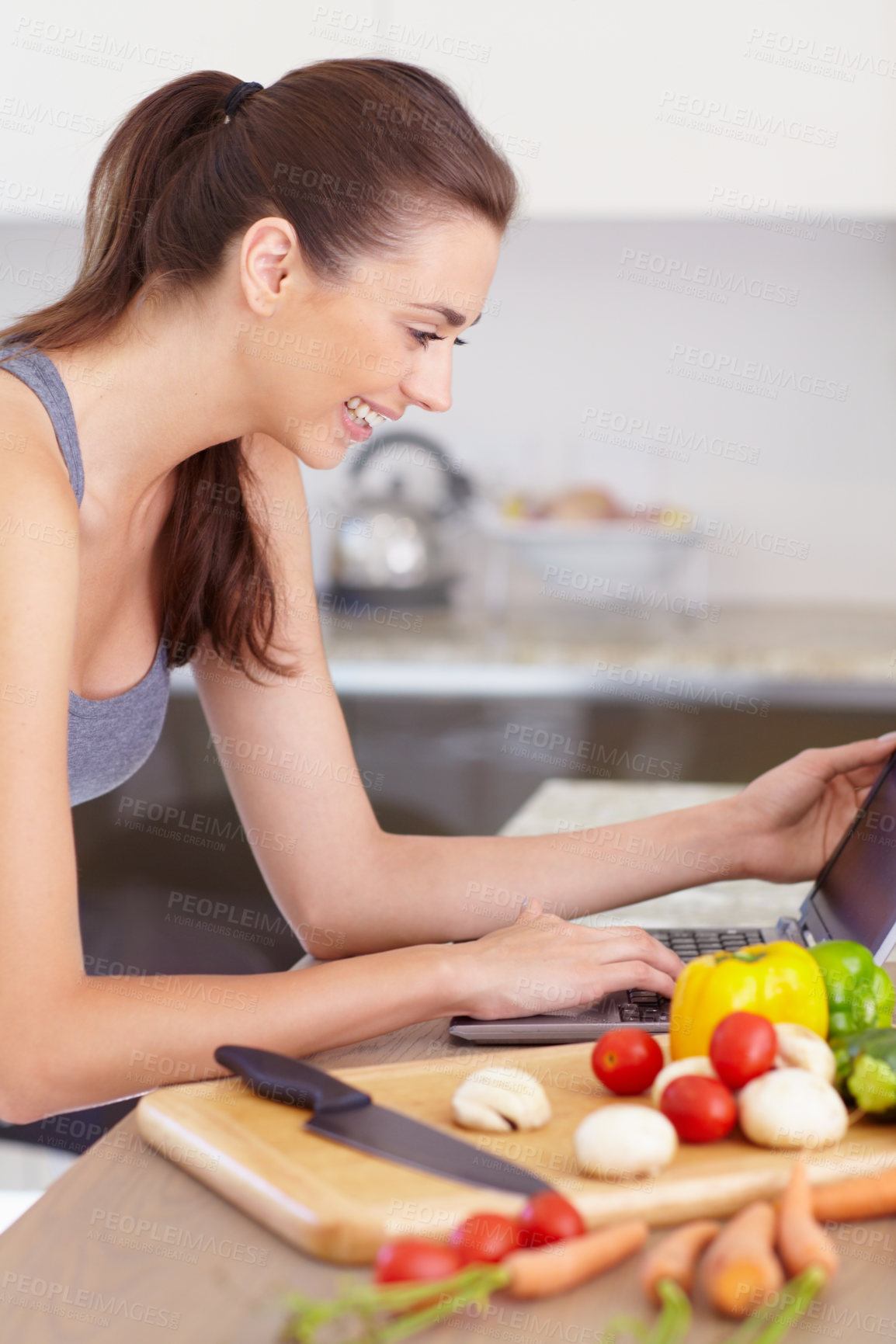 Buy stock photo Laptop, food and a woman reading a recipe in her kitchen with vegetarian ingredients for health. Computer, smile and a happy young person cooking a meal in her apartment for a diet or nutrition