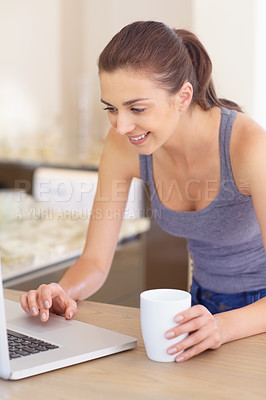 Buy stock photo A beautiful young woman using her laptop and holding a cup of coffee