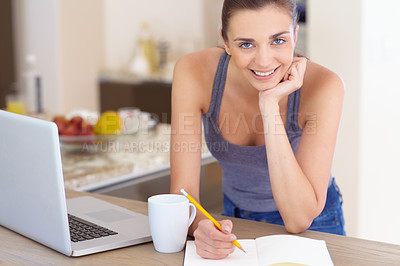 Buy stock photo Portrait, notebook and a woman writing in the kitchen of her home in the morning for education or journaling. Coffee, laptop and diary with a happy young person in her apartment for planning or study