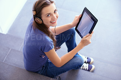 Buy stock photo Portrait of an attractive young woman sitting on some steps with her tablet and listening to music