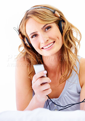 Buy stock photo Young woman listening to music while wearing a pair of headphones and smiling