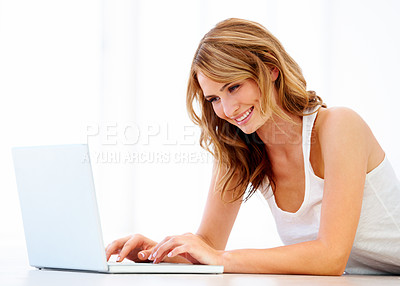 Buy stock photo A young woman using her laptop while on the floor at home