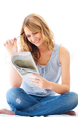 Buy stock photo Newspaper, crossword puzzle and a woman sitting crossed legs in studio isolated on a white background. Smile, thinking a problem solving with a happy female person enjoying a mental hobby to relax