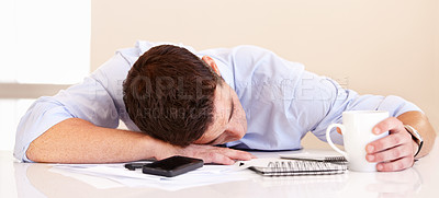 Buy stock photo Exhausted businessman lying on his desk along with his mobile phone