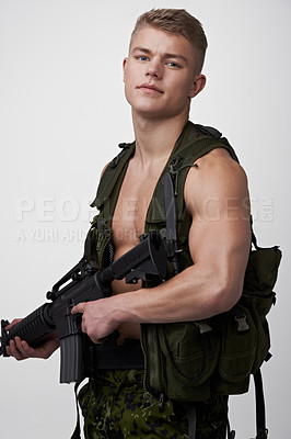 Buy stock photo Handsome young soldier with an automatic rifle looking at the camera