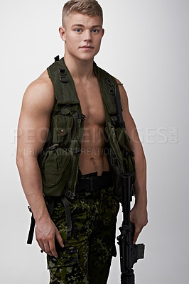 Buy stock photo Young soldier with an automatic rifle looking at the camera