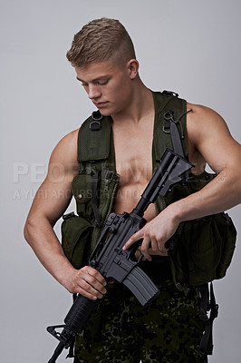 Buy stock photo Young soldier with an automatic rifle looking downwards